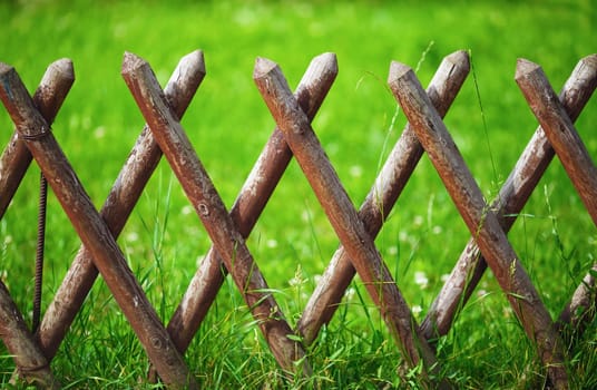 Brown timber wooden fence on a green lawn background.