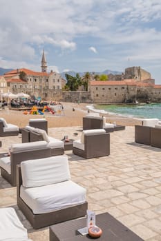 Budva, Montenegro - April 2018 : Large empty lounge chairs waiting for tourists on the beach outside a cafe and restaurant