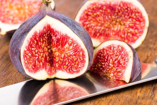 Group of sliced ripe, delicious and sweets figs with a kitchen knife on a old rustic wooden cutting board
