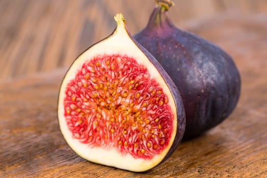 One whole and on half sliced ripe, delicious and sweets figs on a old rustic wooden cutting board