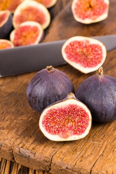 Group of whole and sliced ripe, delicious and sweets figs with a kitchen knife on a old rustic wooden cutting board