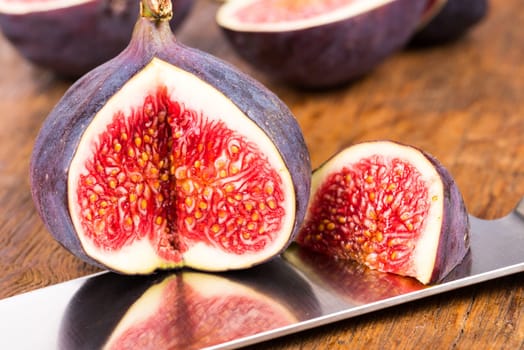 Group of sliced ripe, delicious and sweets figs with a kitchen knife on a old rustic wooden cutting board