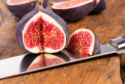 Group of sliced ripe, delicious and sweets figs with a kitchen knife on a old rustic wooden cutting board