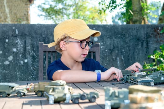 a little boy with a yellow cap plays with toys outside