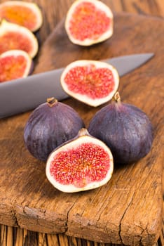 Group of whole and sliced ripe, delicious and sweets figs with a kitchen knife on a old rustic wooden cutting board