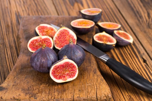 Group of whole and sliced ripe, delicious and sweets figs with a kitchen knife on a old rustic wooden cutting board