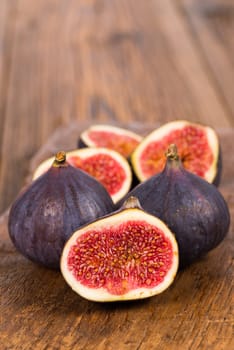 Group of whole and sliced ripe, delicious and sweets figs on a old rustic wooden cutting board