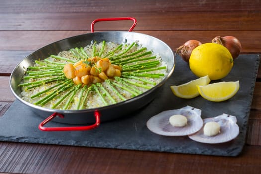 Paella with scollops and asparagus in traditional pan.