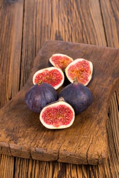 Group of whole and sliced ripe, delicious and sweets figs on a old rustic wooden cutting board