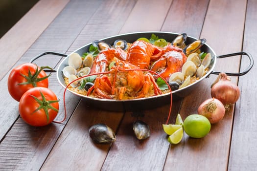 Gourmet seafood Valencia paella with fresh langoustine, clams, mussels and squid on savory saffron rice with peas and lemon slices, close up view