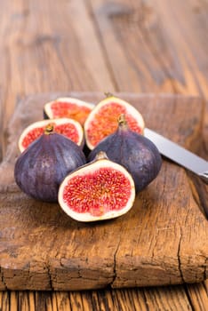 Group of whole and sliced ripe, delicious and sweets figs with a kitchen knife on a old rustic wooden cutting board