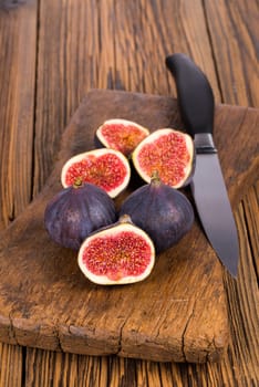 Group of whole and sliced ripe, delicious and sweets figs on a old rustic wooden cutting board