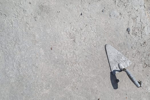 Used masonry trowel on concrete background. Space for text. Flat lay.