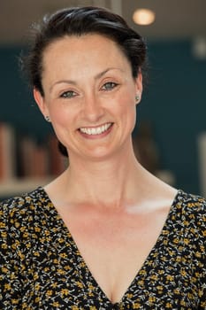 Front view of a mid adult woman smiling at the camera for a headshot. The woman is wearing casual clothing.