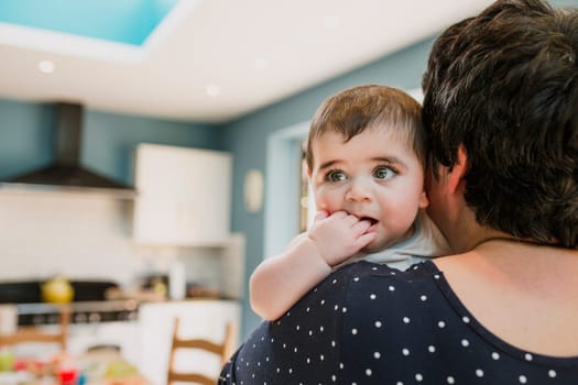 Rear view of an unrecognisable mother holding her baby son. The mother is coforting her child.