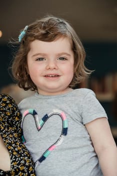 Headshot of a little girl being held by an unrecognisable person for a headshot indoors.