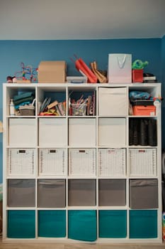 Front view of a storgae unit in a home. The storage unit has many draws and compartments for storage. Some household objects have been stored on top of the unit.