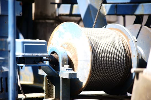 The close-up of the winch of a crane with a coiled steel rope.