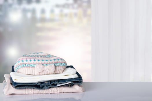 Stack colorful girl clothes. Pile of girl clothes on a white table with space for your display product montage. Abstract bright background. Autumn fashion.