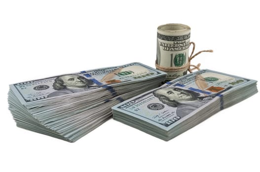 Two packs of one hundred dollar bills and a roll of dollars tied with a rope on a white background. View at an angle, from the side. Isolated.