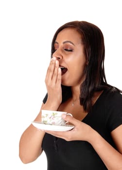 A beautiful young woman holding a coffee cup in her hand and yawning.with her hand over her mouth, isolated for white background.
