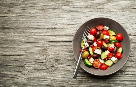 Salad with feta cheese and fresh vegetables on wooden background. Greek salad.