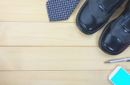 Top view office table with necktie, work shoes, smart phone and pen for business and copy space.