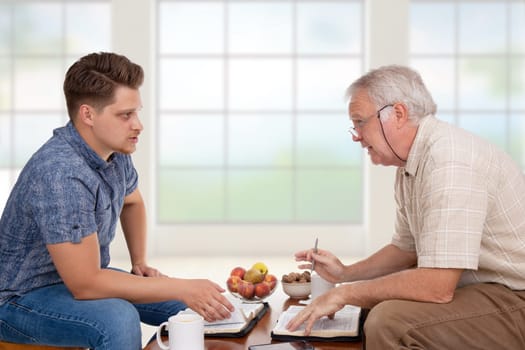 Church servant doing spiritual counseling to a young man studying the Bible