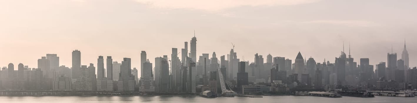 New York City midtown Manhattan skyline panorama view from Boulevard East Old Glory Park over Hudson River on a misty morning.