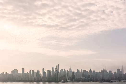 New York City midtown Manhattan skyline panorama view from Boulevard East Old Glory Park over Hudson River on a misty morning.