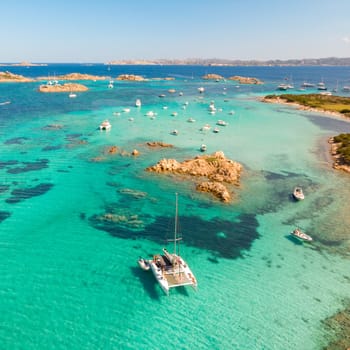 Drone aerial view of catamaran sailing boat in Maddalena Archipelago, Sardinia, Italy. Maddalena Archipelago is composed of Razzoli, Santa Maria and Budelli islands.
