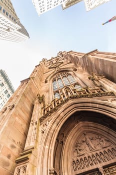Wide angle upward view of Trinity Church at Broadway and Wall Street with surrounding skyscrapers, Lower Manhattan, New York City, USA.