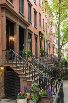 Row of old brownstone buildings along an empty sidewalk block in the Greenwich Village neighborhood of Manhattan, New York City, NYC, USA.