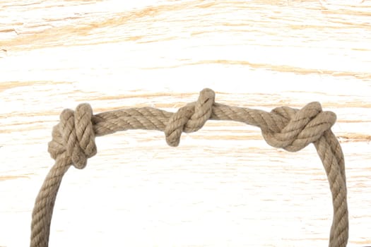 Close-up of node or knot from two ropes in front of bright wooden background. Navy and angler knot.