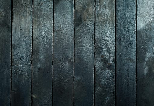Background texture of blackened wood burnt in a fire with close up detail of the surface, woodgrain and knots in a full frame view