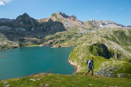 a man hiker climbing a slope, Lake Estaens in the background