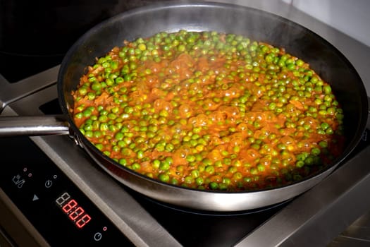 Low peas and tomato sauce boiled in the pan on the electric hob