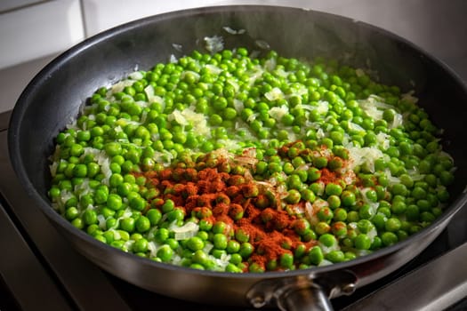 Chopped onion and pepper powder added to green peas in the pan