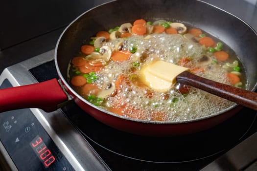 Vegetables with mushrooms cooked in a pan with a silicone spatula
