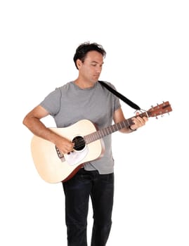 A young handsome man standing with his guitar and playing a song.in jeans and t-shirt, isolated for white background.