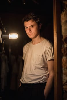 Portrait of a fashion designer in his dressing room, illuminated by a bulb light.