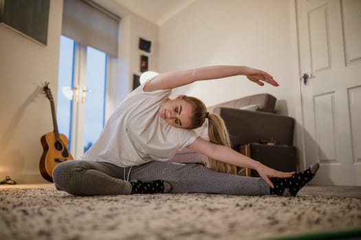 University student is doing yoga in her living room.