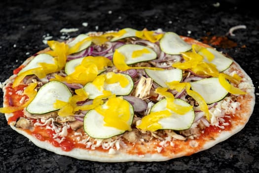 Vegetarian pizza on black table, ready to be baked