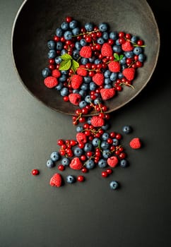 Mix of fresh berries in a bowl on black background