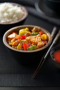 Chinese food with salmon meat and vegetables on black background