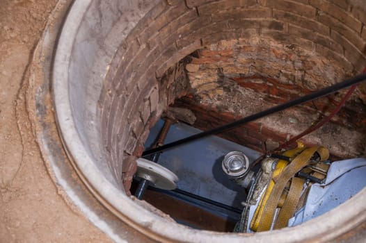 Rehabilitation work on an exposed sewer with manhole and automatic feed unit for drawing in a plastic pipe.