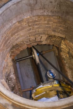 Rehabilitation work on an exposed sewer with manhole and automatic feed unit for drawing in a plastic pipe.