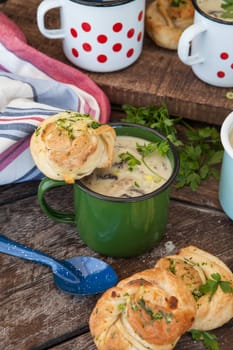 Creamy mushroom soup with fresh parley in rustic enamel mugs