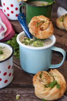 Creamy mushroom soup with fresh parley in rustic enamel mugs