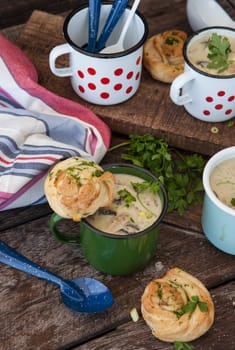 Creamy mushroom soup with fresh parley in rustic enamel mugs